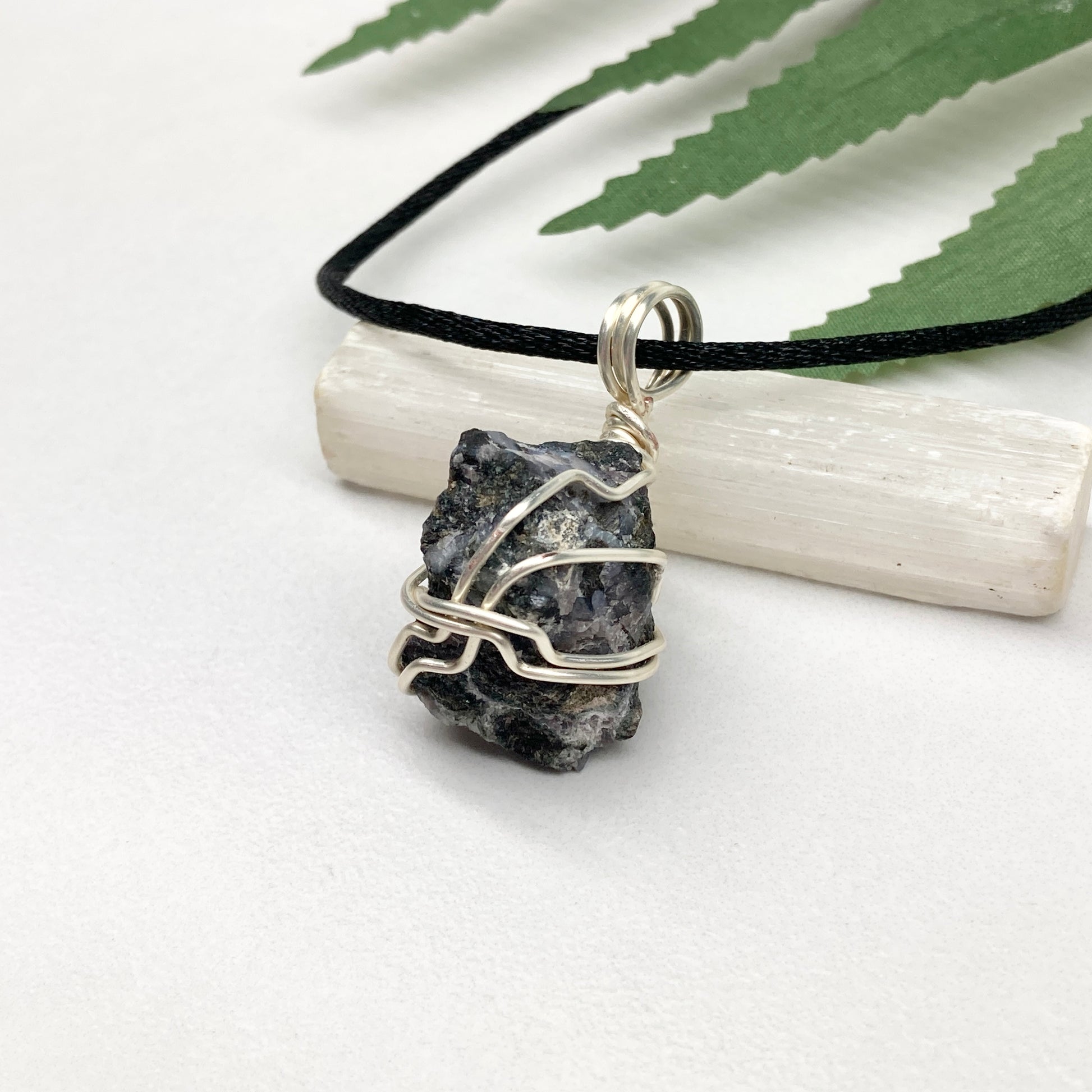 Indigo Gabbro necklace. Raw Indigo Gabbro stone wrapped with tarnish resistant wire. Hangs on a black chain. Also known as Mystic Merlinite. Gray and black marbled crystal.