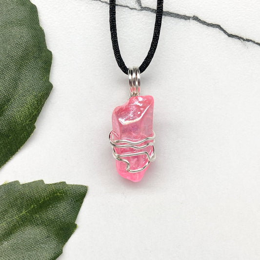 Pink Aura Quartz necklace featuring a natural crystal point coated in pink aura for a glowing effect, hand-wrapped with silver wire, on a black chain for everyday wear.