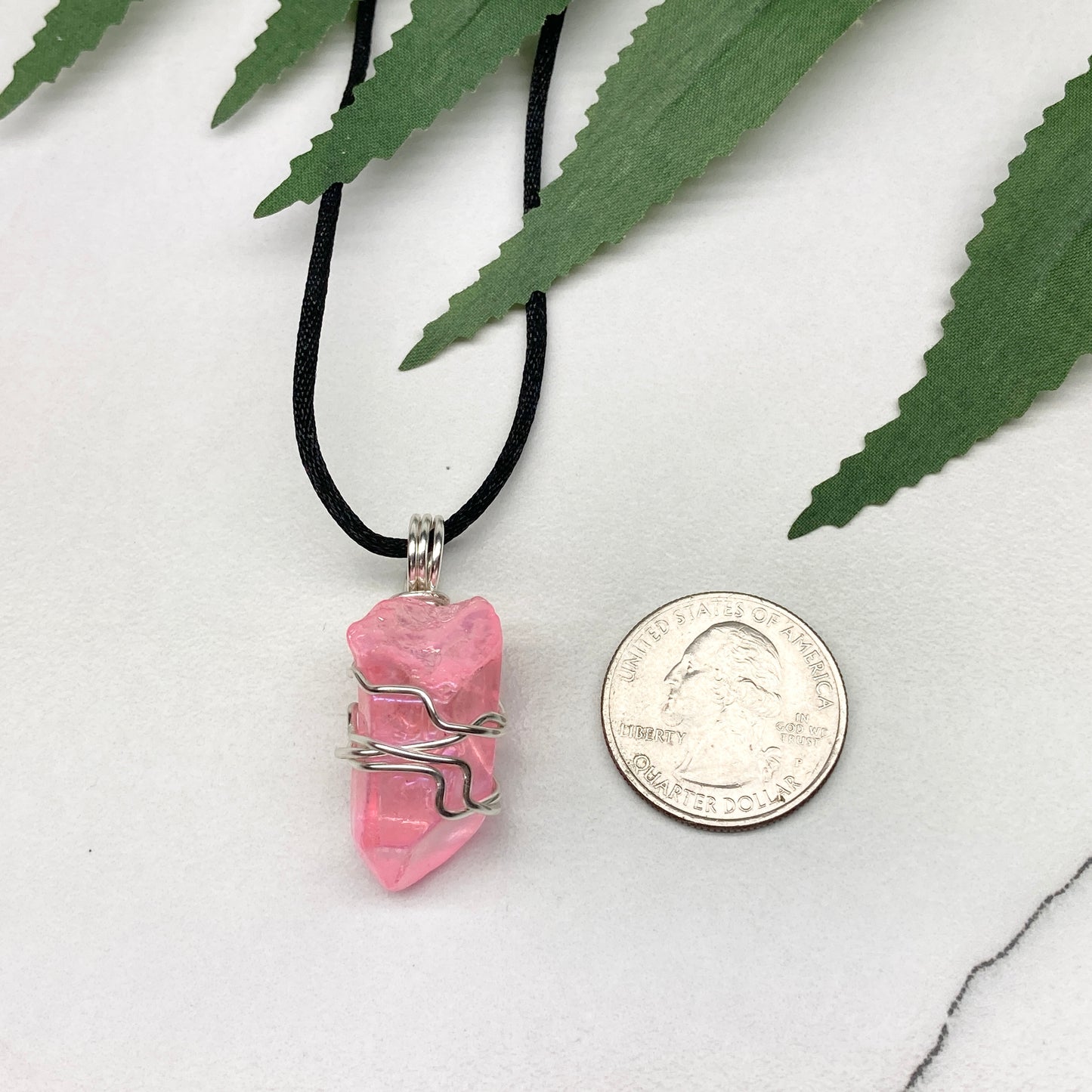 Pink Aura Quartz necklace. Pink Aura Quartz crystal wrapped with silver colored copper wire. Hangs on a black chain. Wire wrapped pendant.