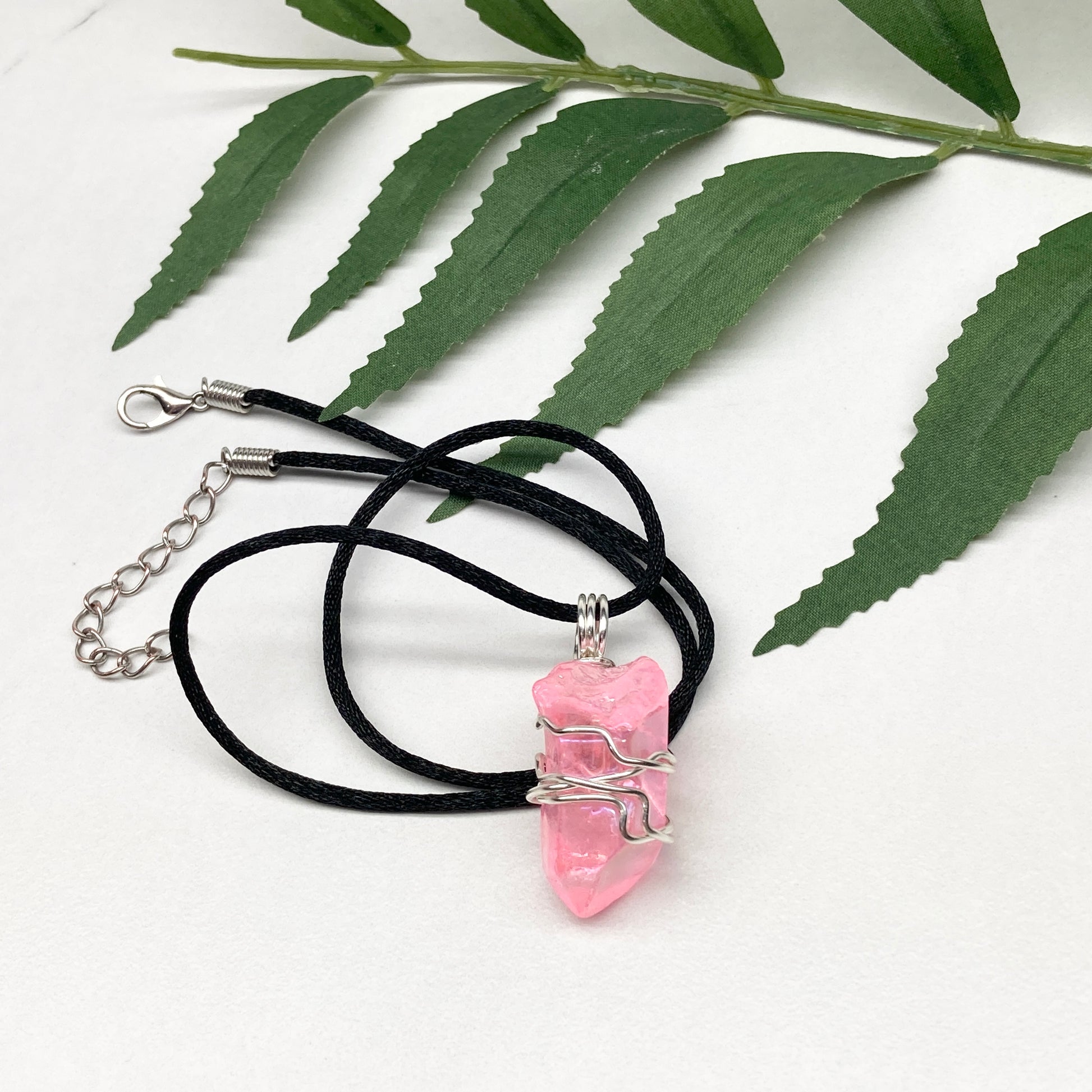 Pink Aura Quartz necklace. Pink Aura Quartz crystal wrapped with silver colored copper wire. Hangs on a black chain. Wire wrapped pendant.