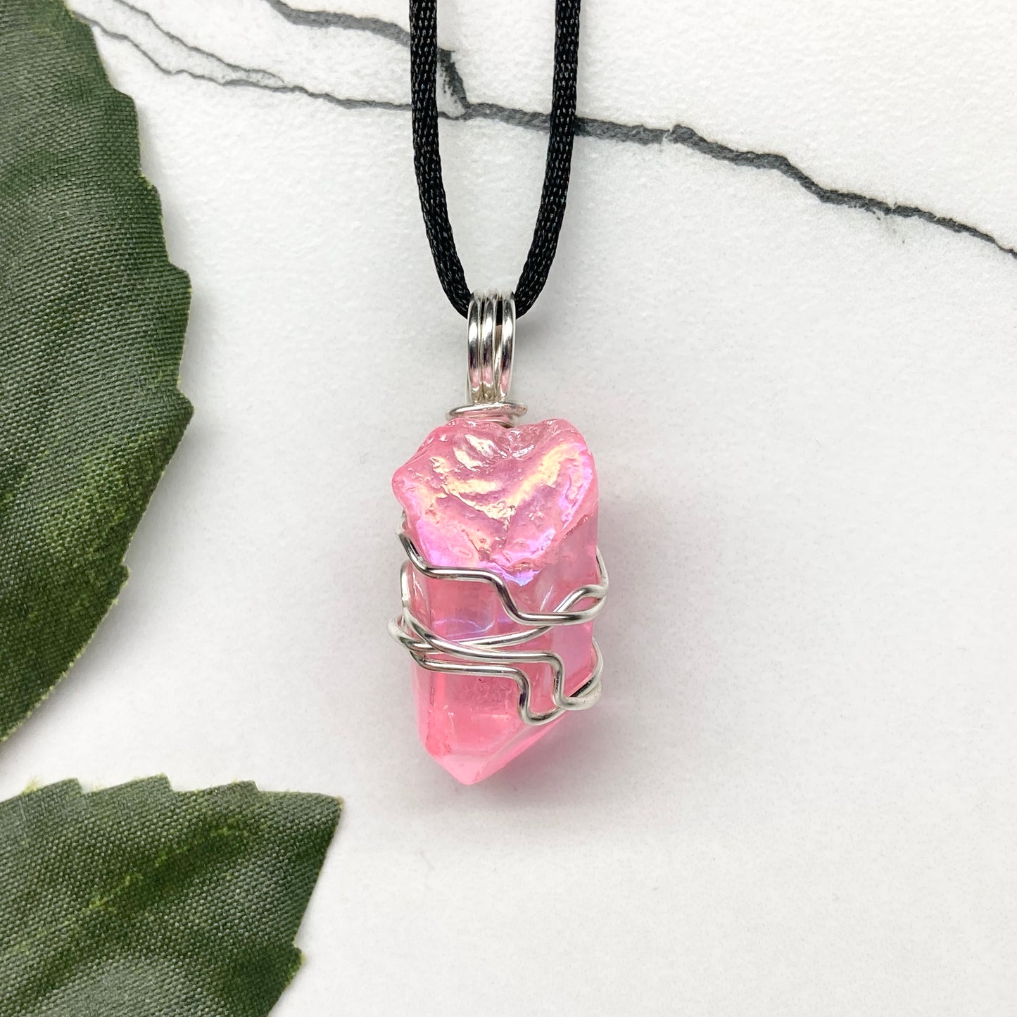 Pink Aura Quartz necklace. Pink Aura Quartz crystal wrapped with silver colored copper wire. Hangs on a black chain. Wire wrapped pendant.