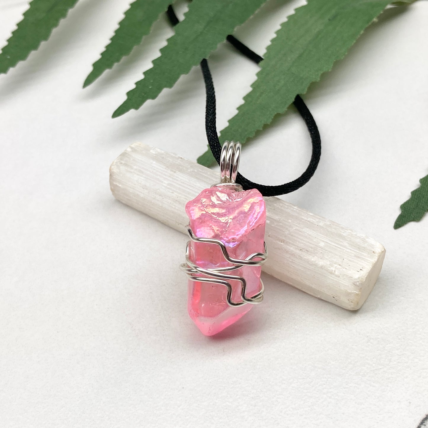 Pink Aura Quartz necklace. Pink Aura Quartz crystal wrapped with silver colored copper wire. Hangs on a black chain. Wire wrapped pendant.