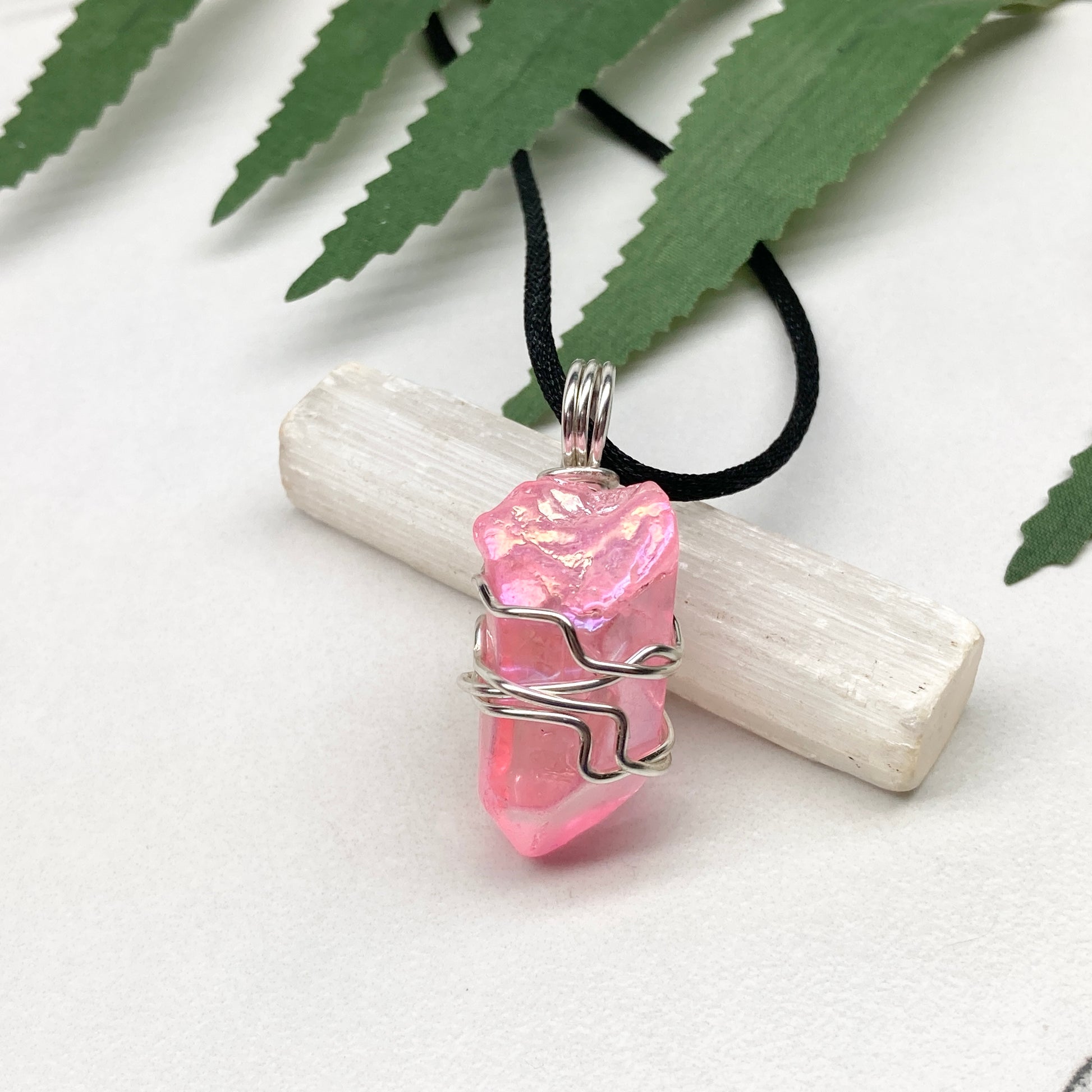 Pink Aura Quartz necklace. Pink Aura Quartz crystal wrapped with silver colored copper wire. Hangs on a black chain. Wire wrapped pendant.