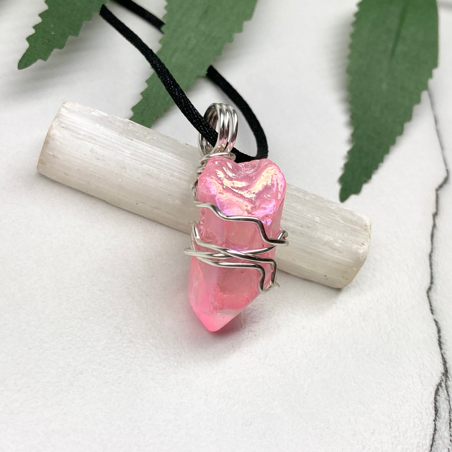 Pink Aura Quartz necklace. Pink Aura Quartz crystal wrapped with silver colored copper wire. Hangs on a black chain. Wire wrapped pendant.