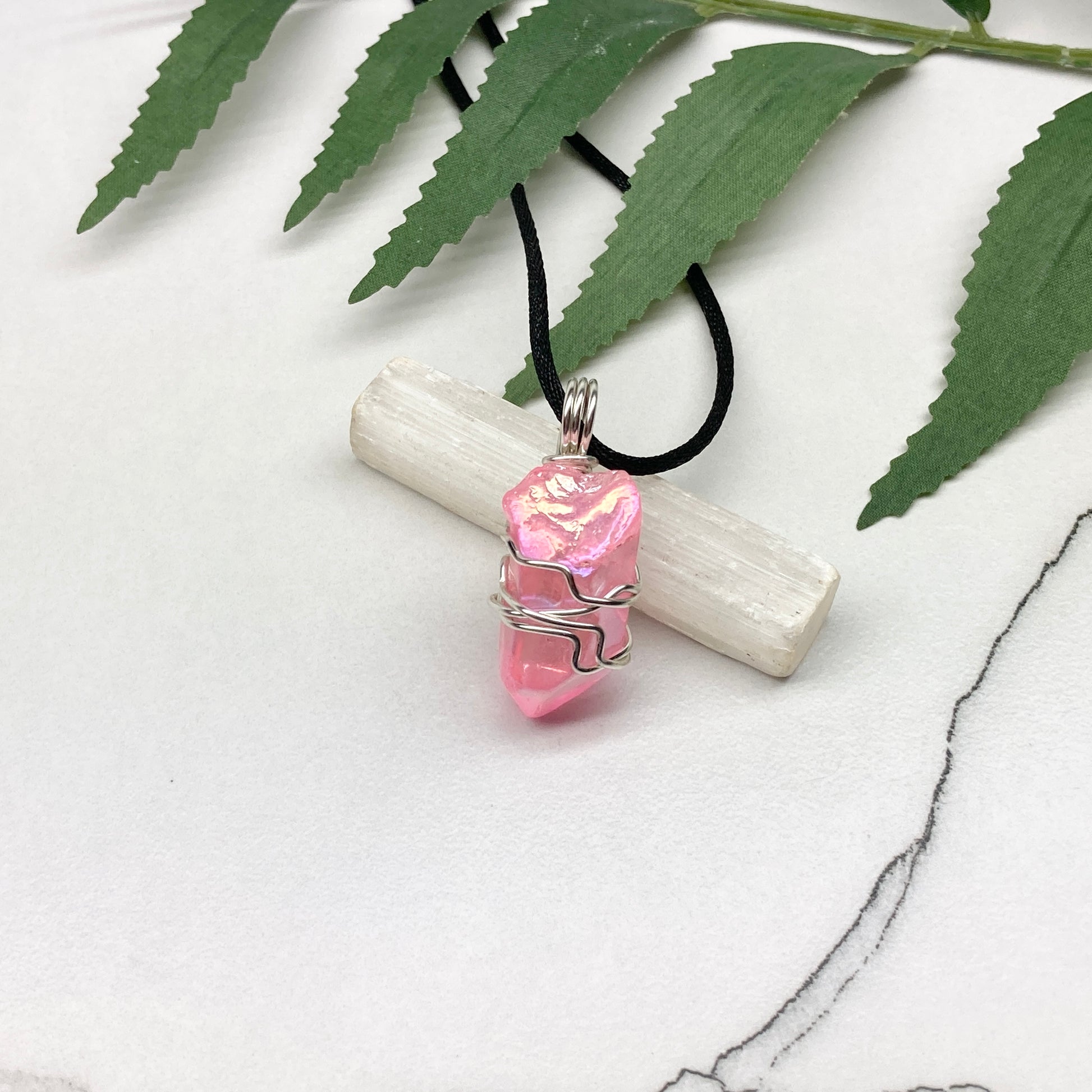 Pink Aura Quartz necklace. Pink Aura Quartz crystal wrapped with silver colored copper wire. Hangs on a black chain. Wire wrapped pendant.