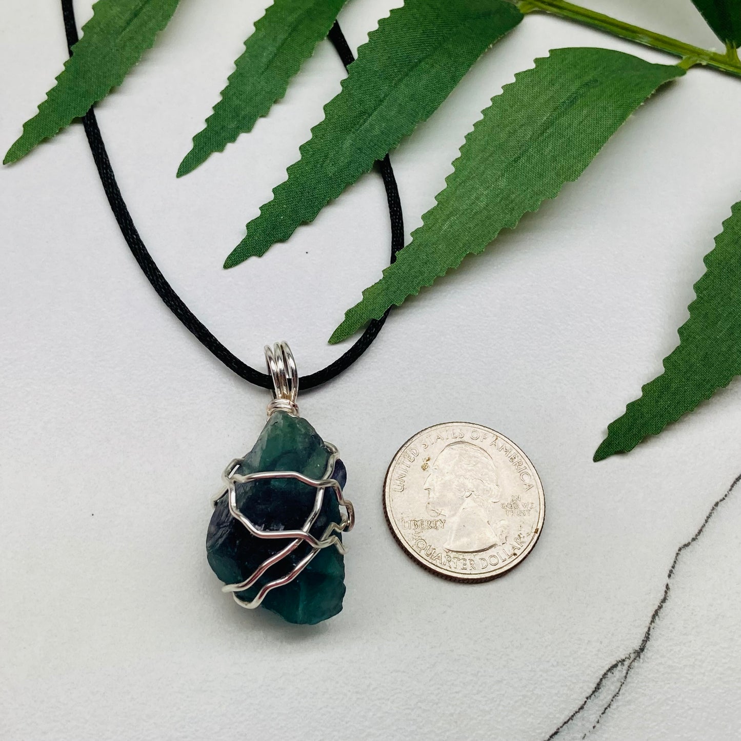 Rainbow Moonstone necklace. Raw blue and green stone wrapped with silver copper wire. Hangs on black chain.