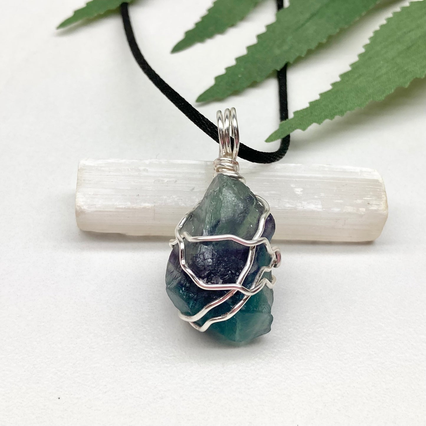Rainbow Moonstone necklace. Raw blue and green stone wrapped with silver copper wire. Hangs on black chain.