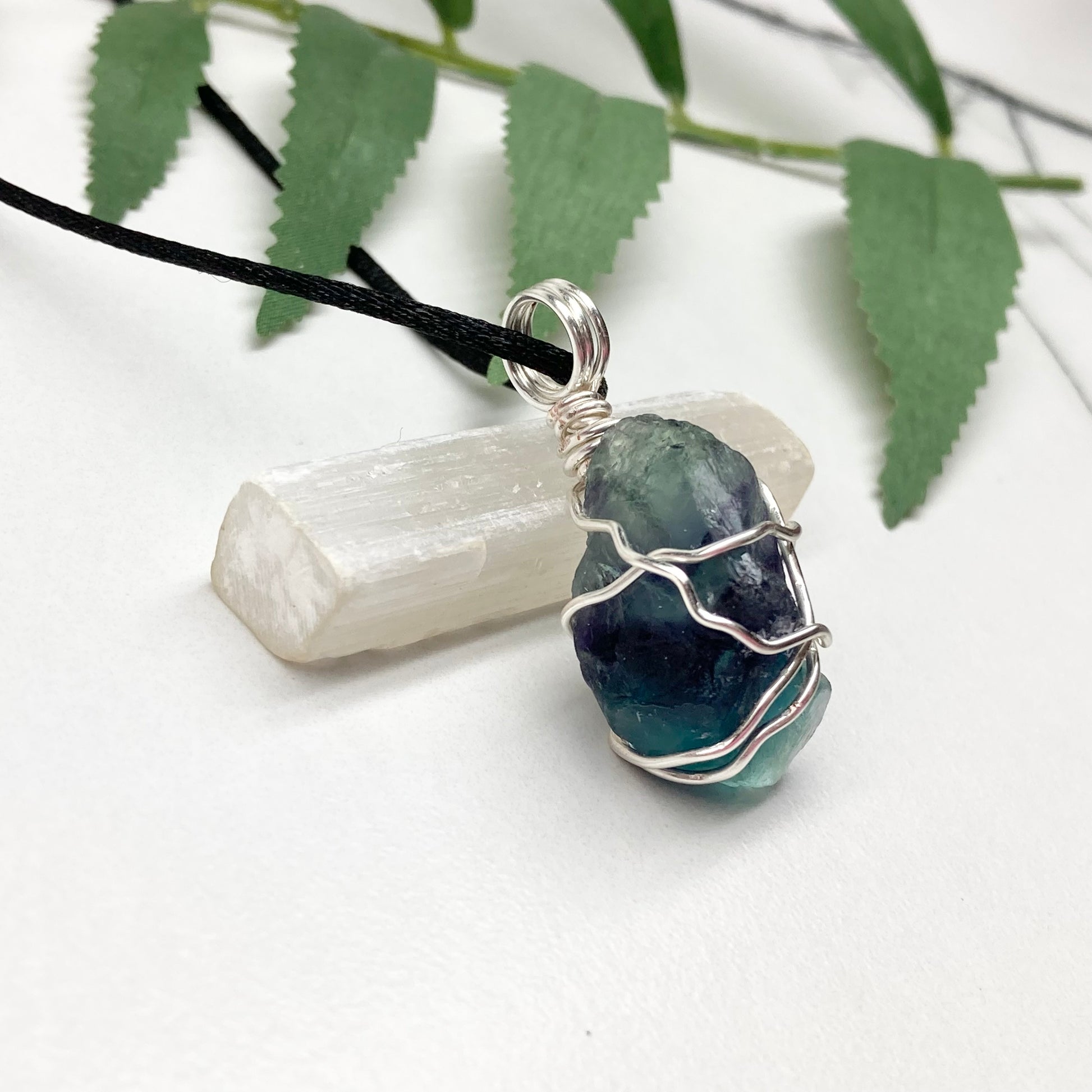Rainbow Moonstone necklace. Raw blue and green stone wrapped with silver copper wire. Hangs on black chain.