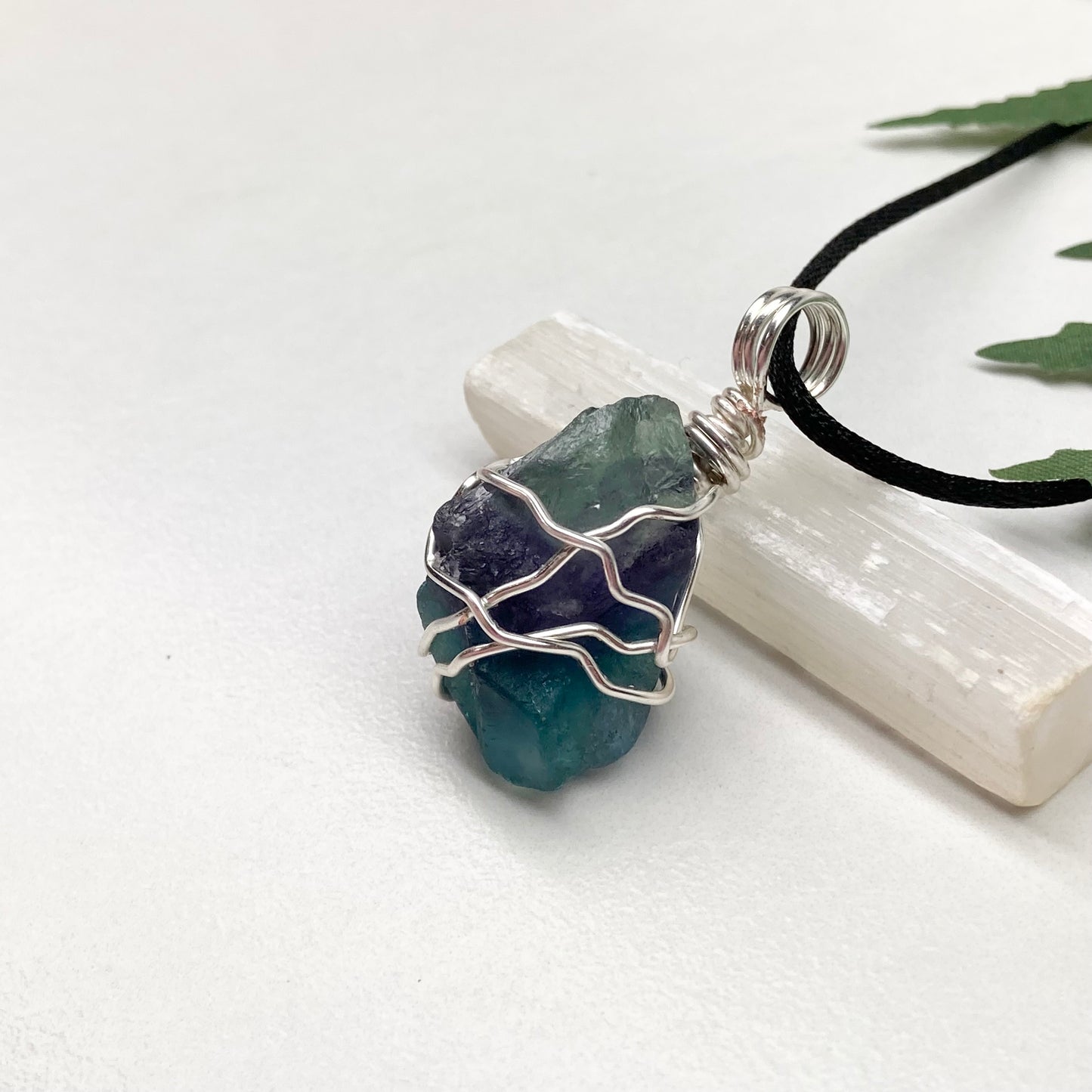 Rainbow Moonstone necklace. Raw blue and green stone wrapped with silver copper wire. Hangs on black chain.
