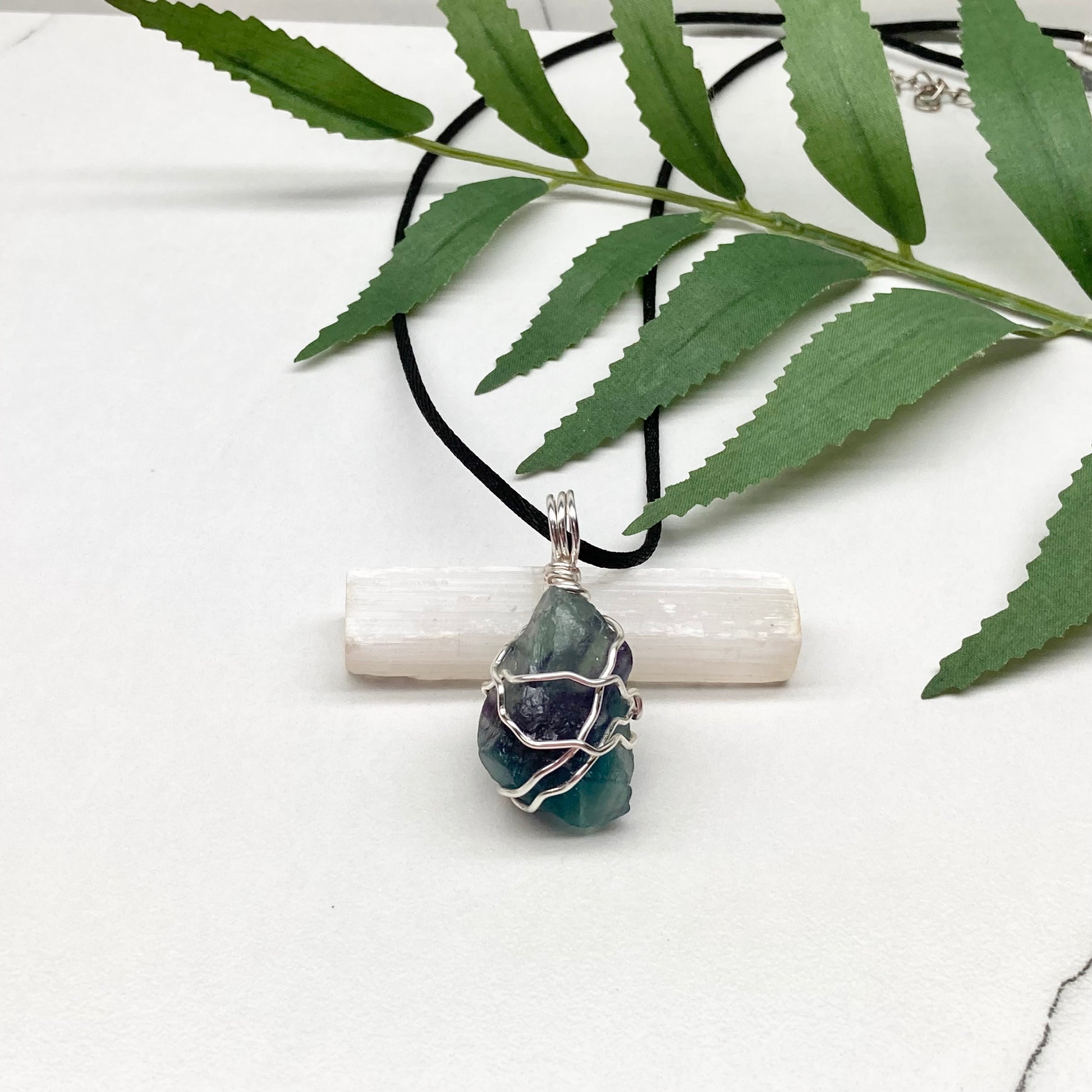 Rainbow Moonstone necklace. Raw blue and green stone wrapped with silver copper wire. Hangs on black chain.