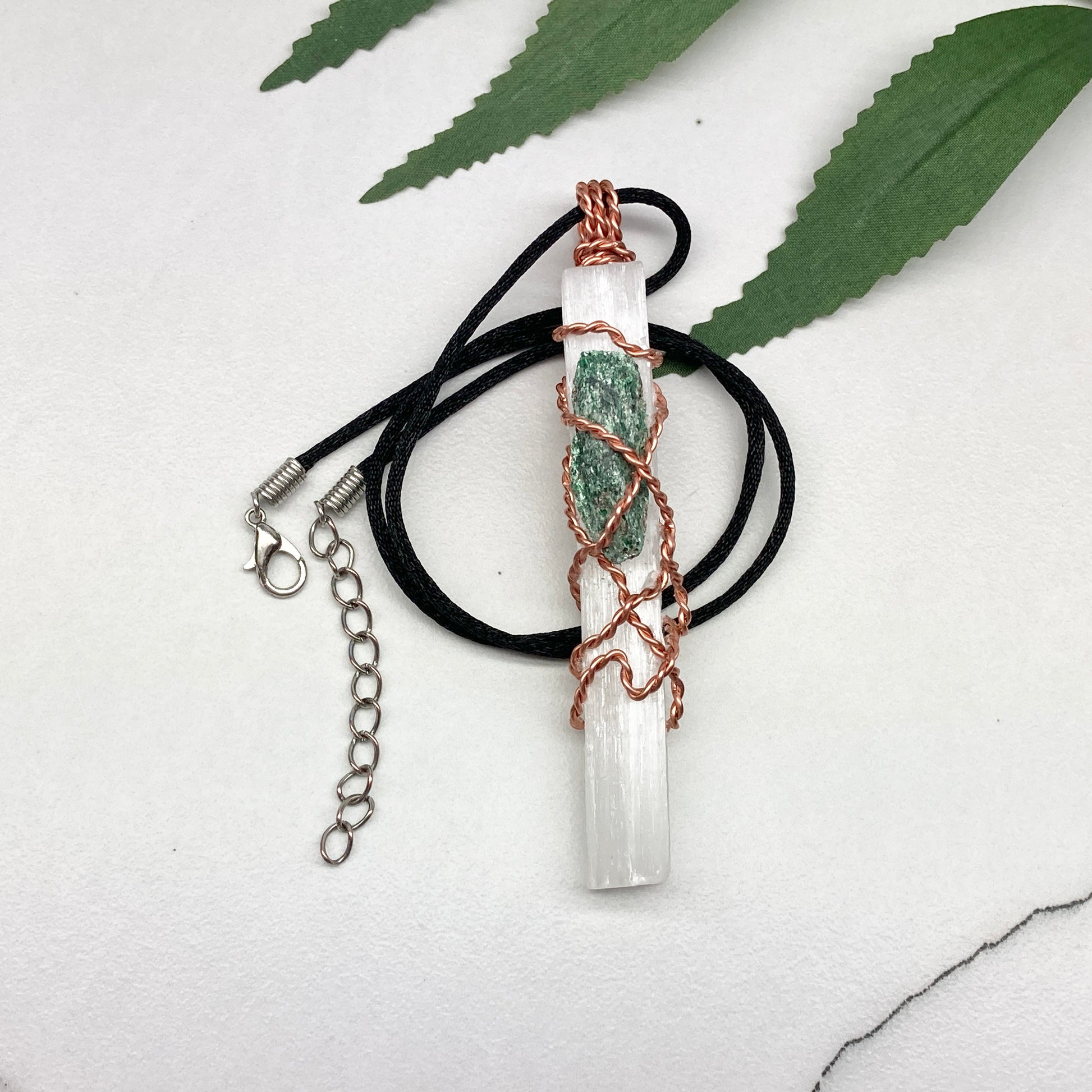 Selenite Fuchsite necklace. A Selenite stick and a raw Fuchsite wrapped together with copper wire. White and green double crystal pendant. Hangs on a black chain. 