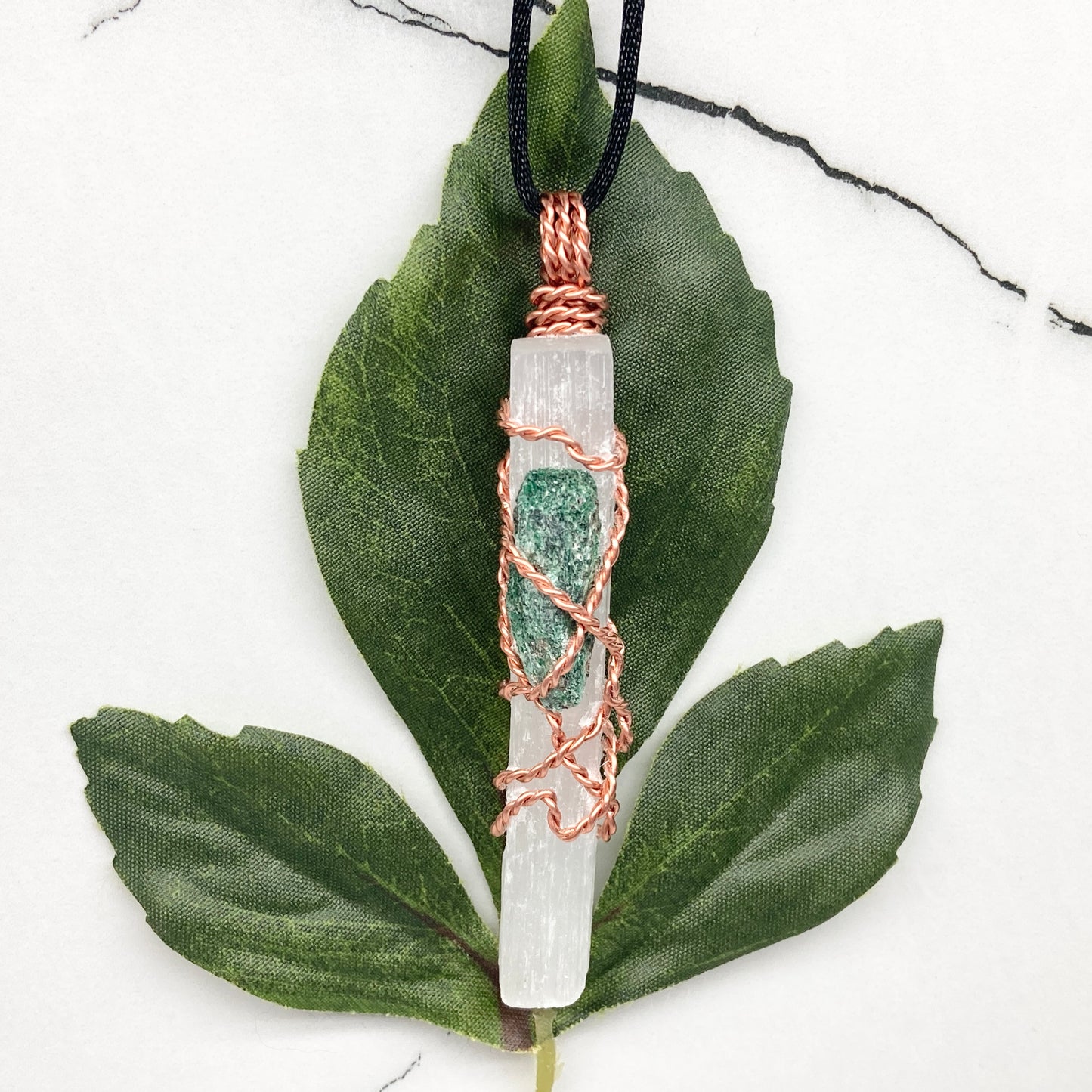 Selenite Fuchsite necklace. A Selenite stick and a raw Fuchsite wrapped together with copper wire. White and green double crystal pendant. Hangs on a black chain. 