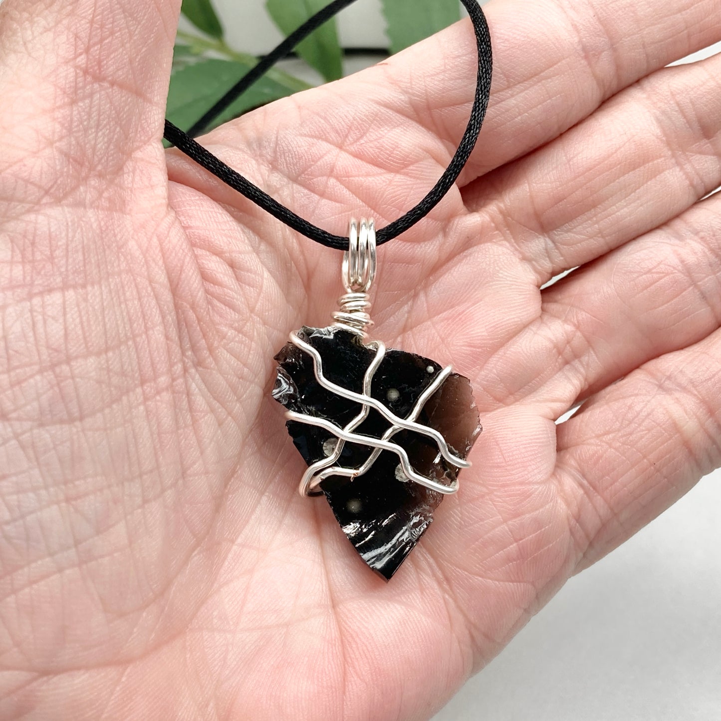 Raw Snowflake Obsidian necklace wrapped in silver-colored copper wire. Handmade crystal pendant created during the Moon in Taurus with natural black and white stone patterns.