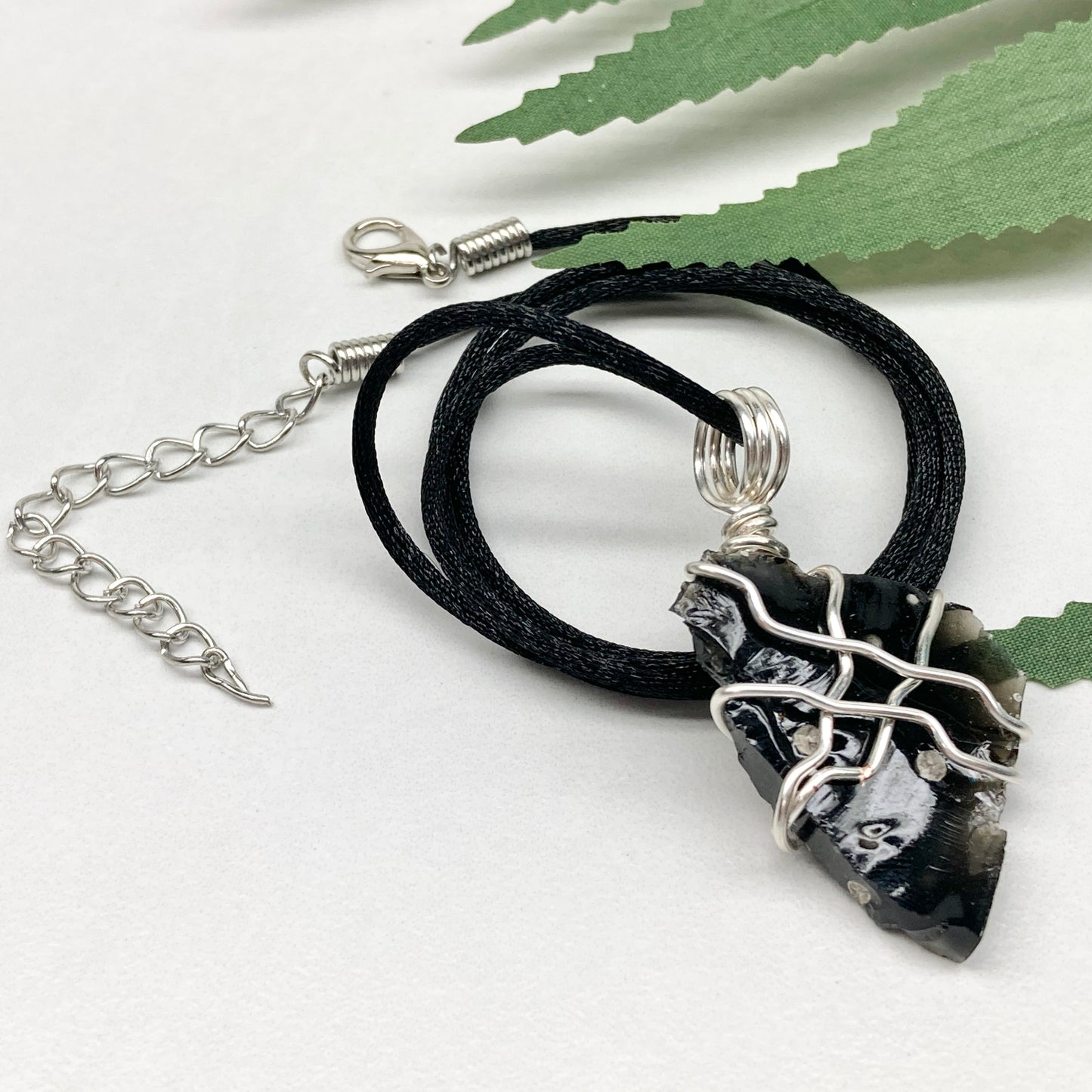 Raw Snowflake Obsidian necklace wrapped in silver-colored copper wire. Handmade crystal pendant created during the Moon in Taurus with natural black and white stone patterns.