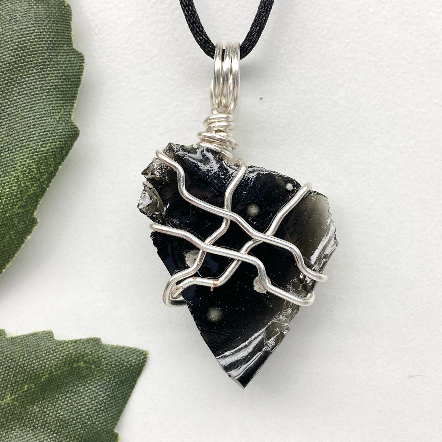 Raw Snowflake Obsidian necklace wrapped in silver-colored copper wire. Handmade crystal pendant created during the Moon in Taurus with natural black and white stone patterns.