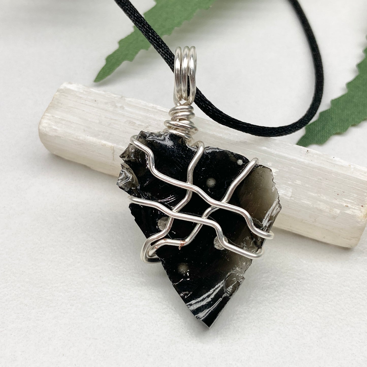 Raw Snowflake Obsidian necklace wrapped in silver-colored copper wire. Handmade crystal pendant created during the Moon in Taurus with natural black and white stone patterns.
