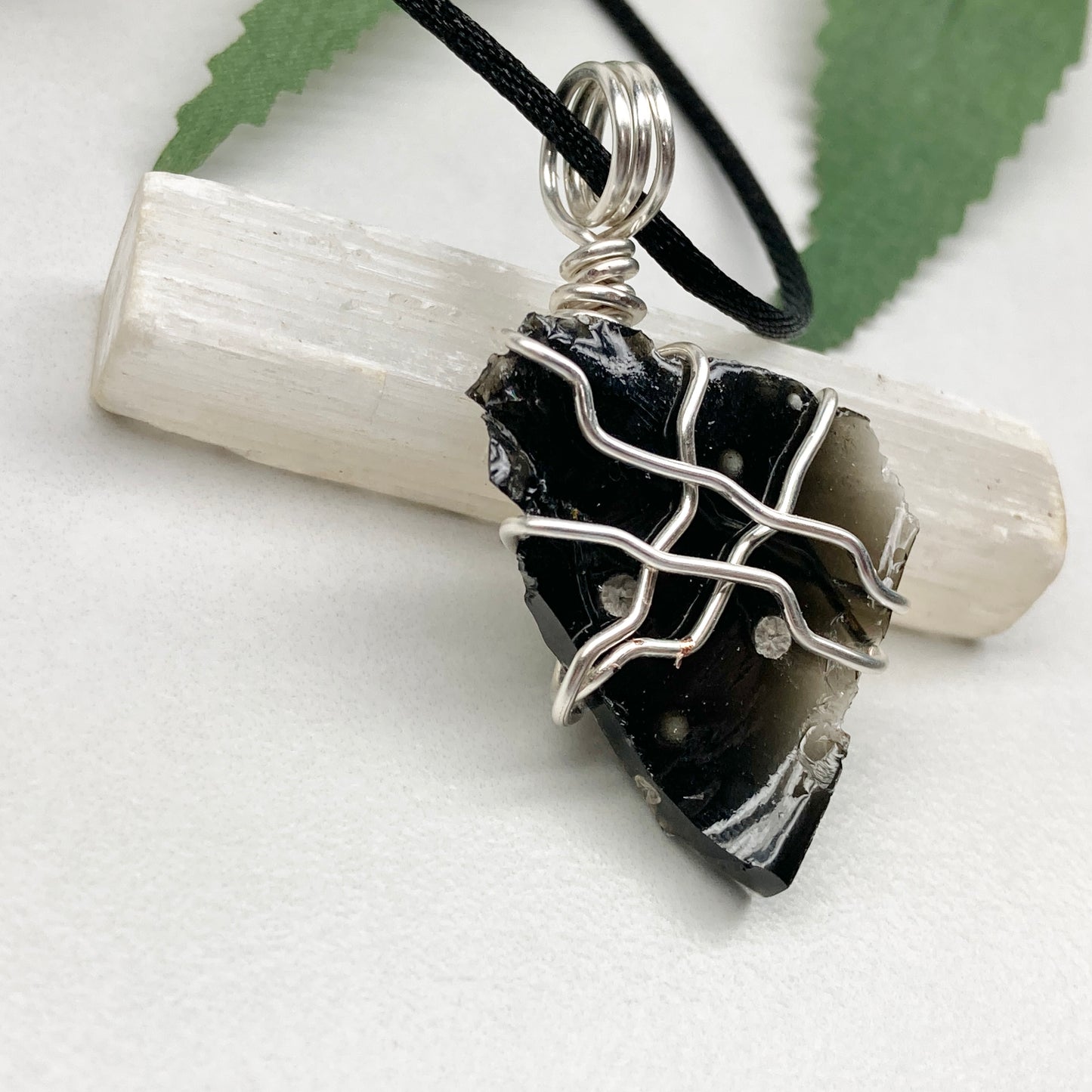 Raw Snowflake Obsidian necklace wrapped in silver-colored copper wire. Handmade crystal pendant created during the Moon in Taurus with natural black and white stone patterns.