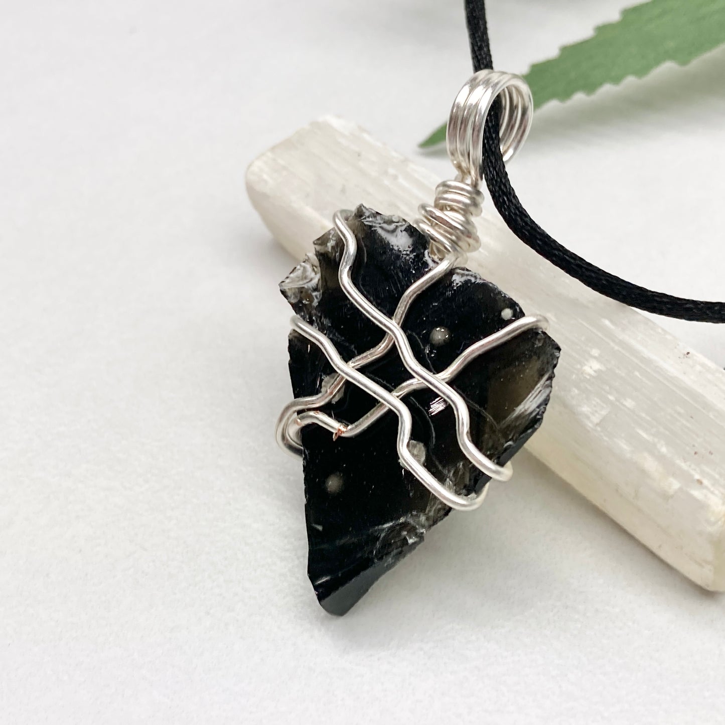 Raw Snowflake Obsidian necklace wrapped in silver-colored copper wire. Handmade crystal pendant created during the Moon in Taurus with natural black and white stone patterns.