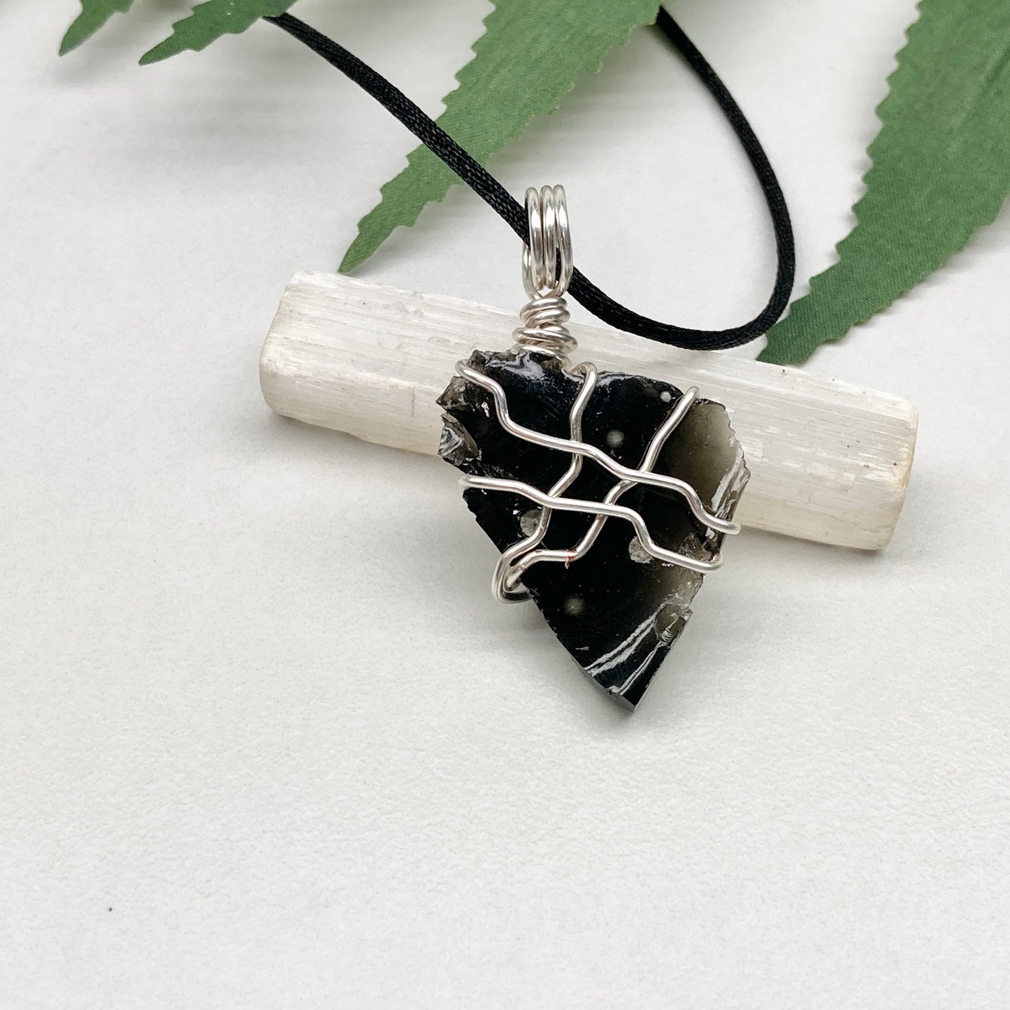 Raw Snowflake Obsidian necklace wrapped in silver-colored copper wire. Handmade crystal pendant created during the Moon in Taurus with natural black and white stone patterns.