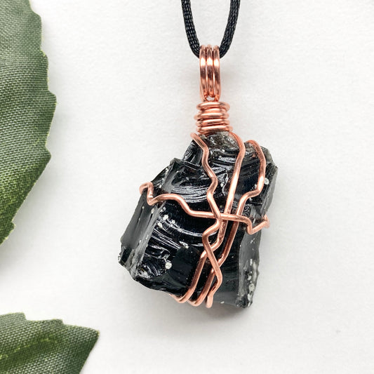 Snowflake Obsidian necklace. Black stone with gray spots wrapped with pure copper wire. Hangs on a black chain. Spiritual handmade jewelry.