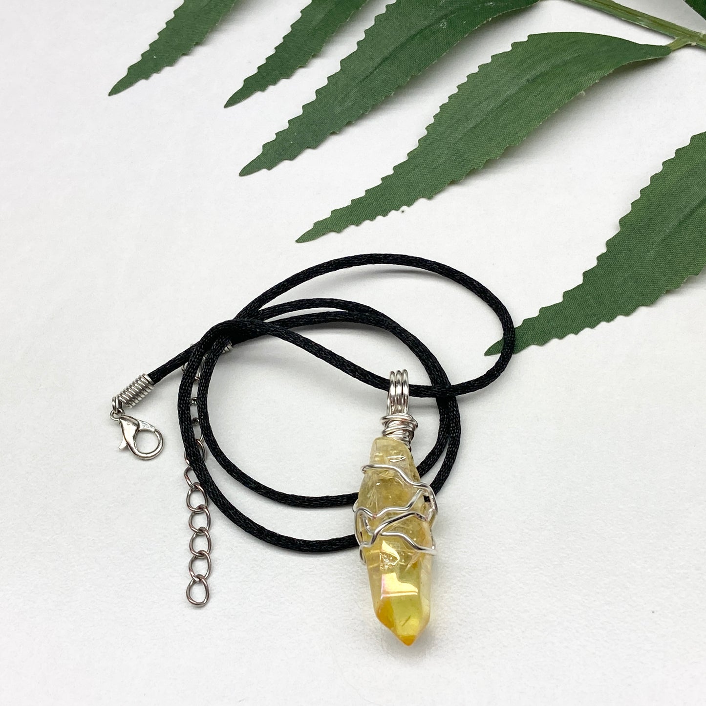 Yellow Aura Quartz necklace. Yellow crystal wrapped with silver colored copper wire. Hangs on a black chain. Handmade yellow stone pendant.