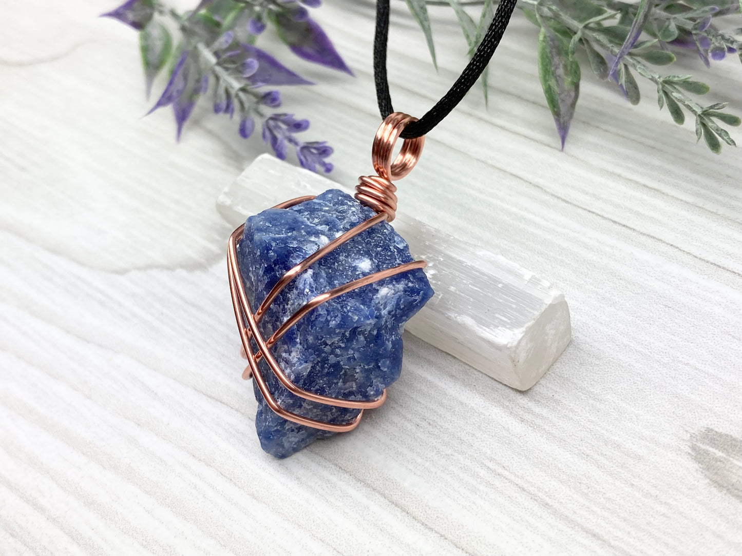 Raw Sodalite Necklace. Left Side View. Real Sodalite Crystal Hand Wrapped With Pure Copper Wire. Gemstone Is Blue With White In It. Comes On A Black Chain. Sagittarius Zodiac Stone Unisex Jewelry.