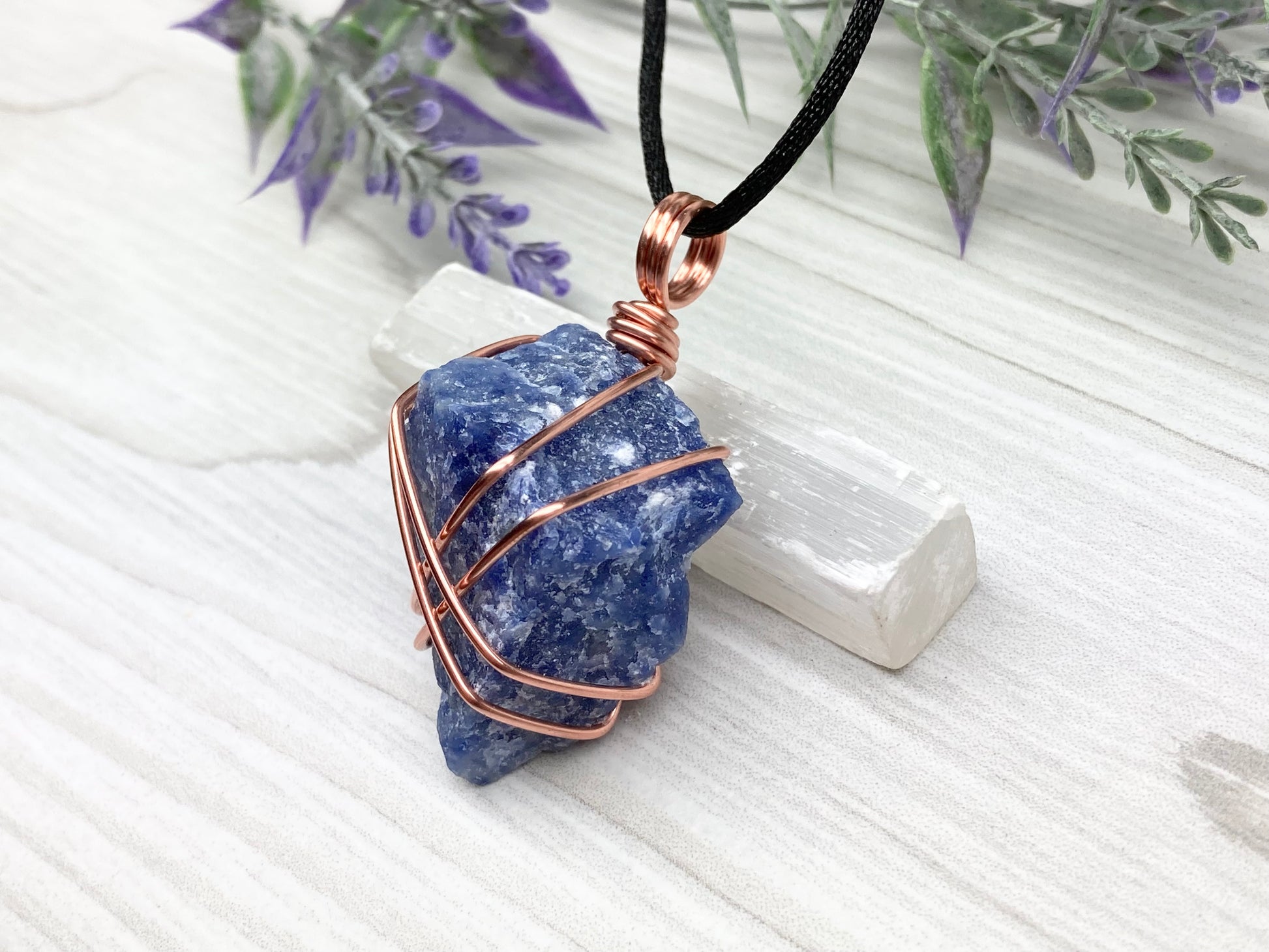 Raw Sodalite Necklace. Left Side View. Real Sodalite Crystal Hand Wrapped With Pure Copper Wire. Gemstone Is Blue With White In It. Comes On A Black Chain. Sagittarius Zodiac Stone Unisex Jewelry.