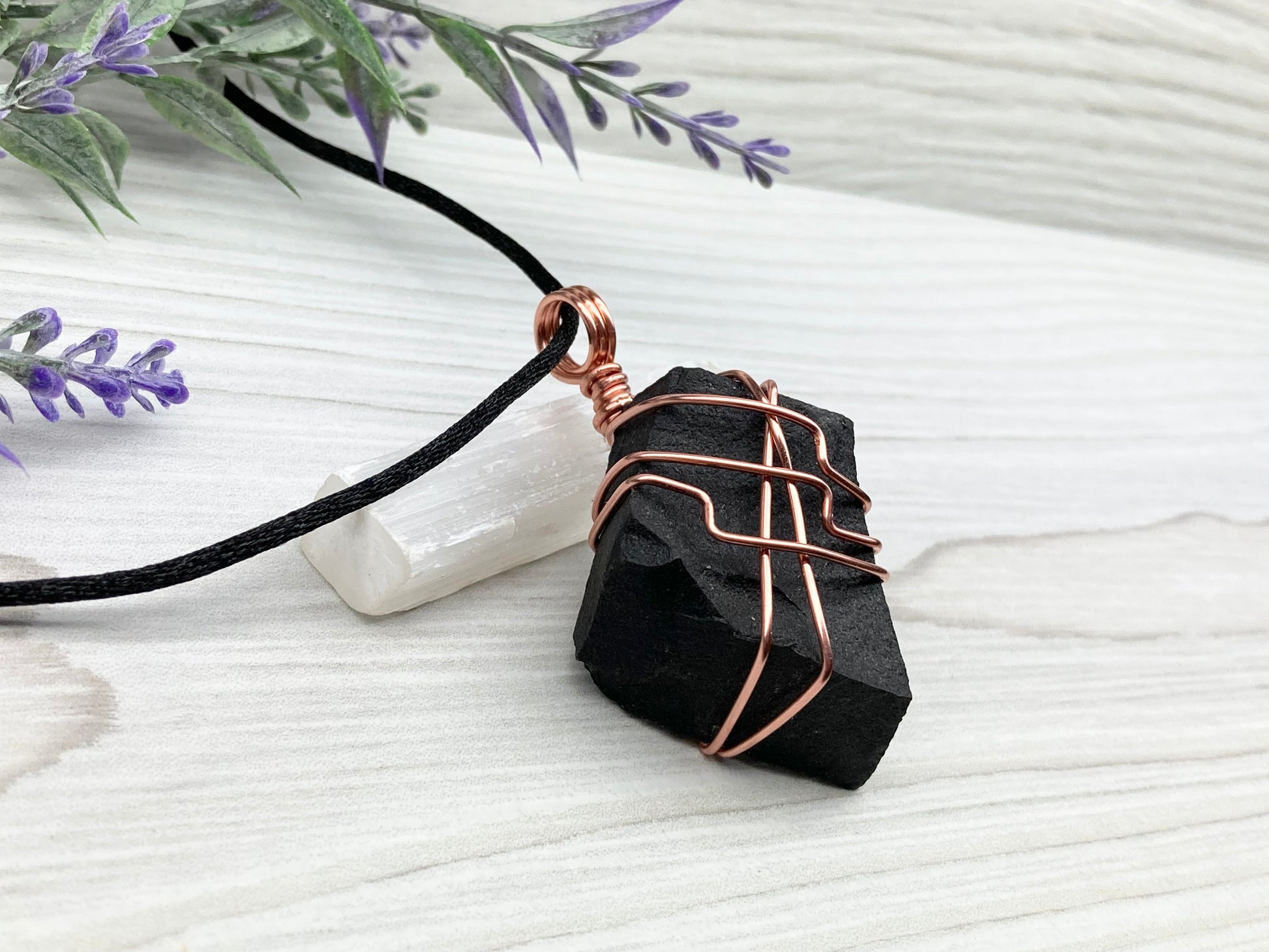 Black Agate stone wrapped with copper wire. Comes on a black satin silk necklace.