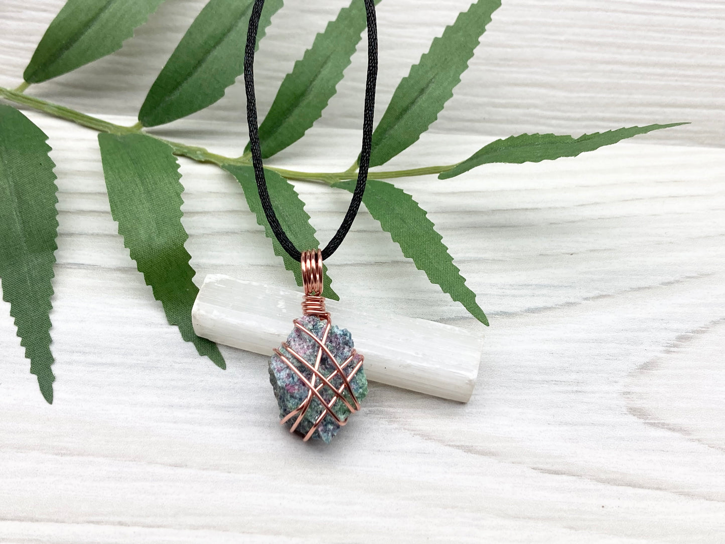 Raw Ruby Zoisite Necklace. This Ruby Zoisite Crystal Is Hand Wrapped With Pure Copper Wire For A Pendant. This Stone is Blue, Red And Green Colored. Comes On A Black Chain. Spiritual New Age Style Jewelry.