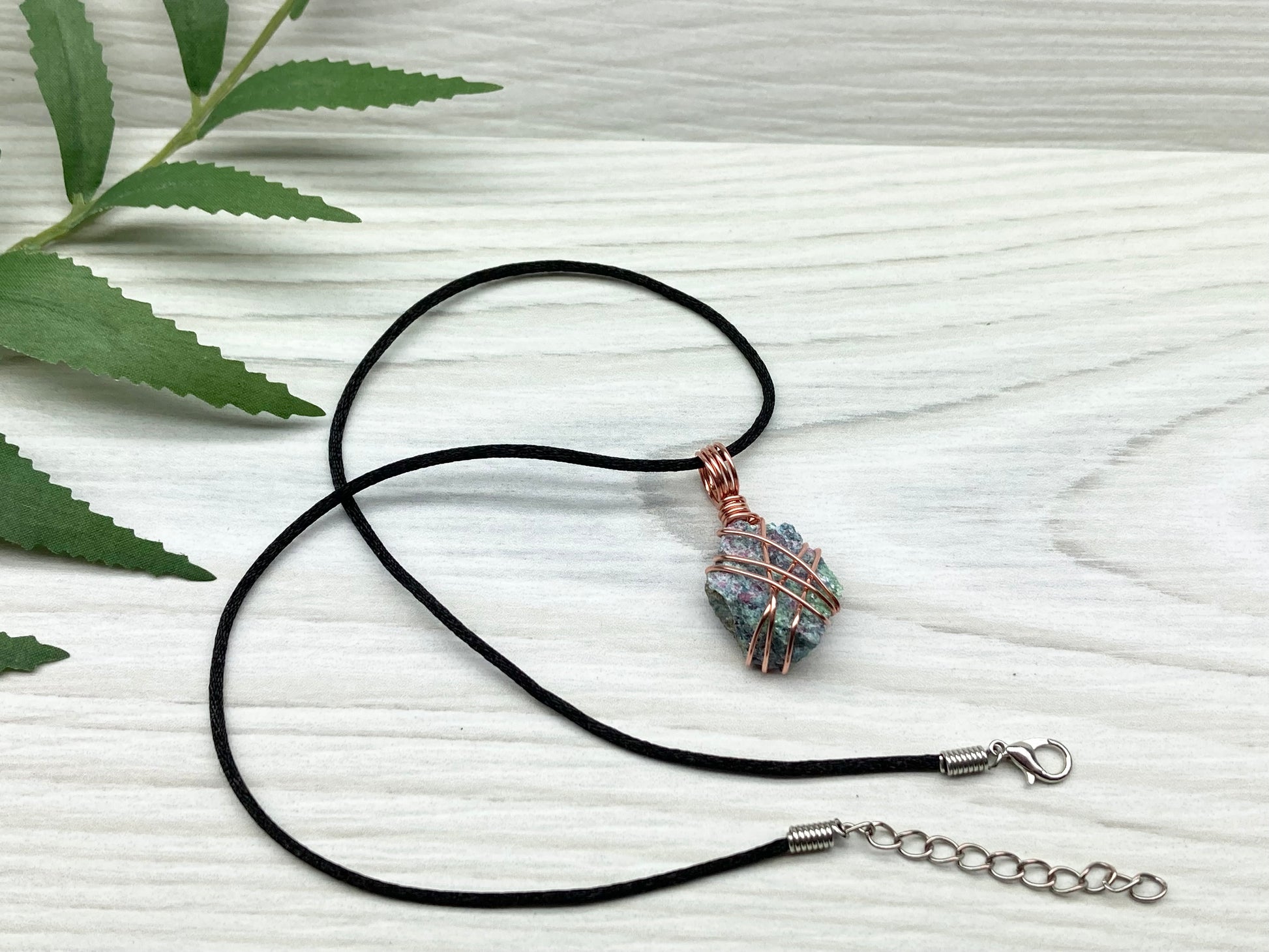 Raw Ruby Zoisite Necklace. This Ruby Zoisite Crystal Is Hand Wrapped With Pure Copper Wire For A Pendant. This Stone is Blue, Red And Green Colored. Comes On A Black Chain. Spiritual New Age Style Jewelry.