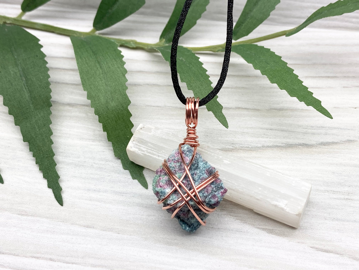 Rough Raw Ruby Zoisite Necklace. This Ruby Zoisite Crystal Is Hand Wrapped With Pure Copper Wire. This Stone is Blue and Red Colored. Gemstone Comes On A Black Chain. Spiritual New Age Style Unisex Jewelry.