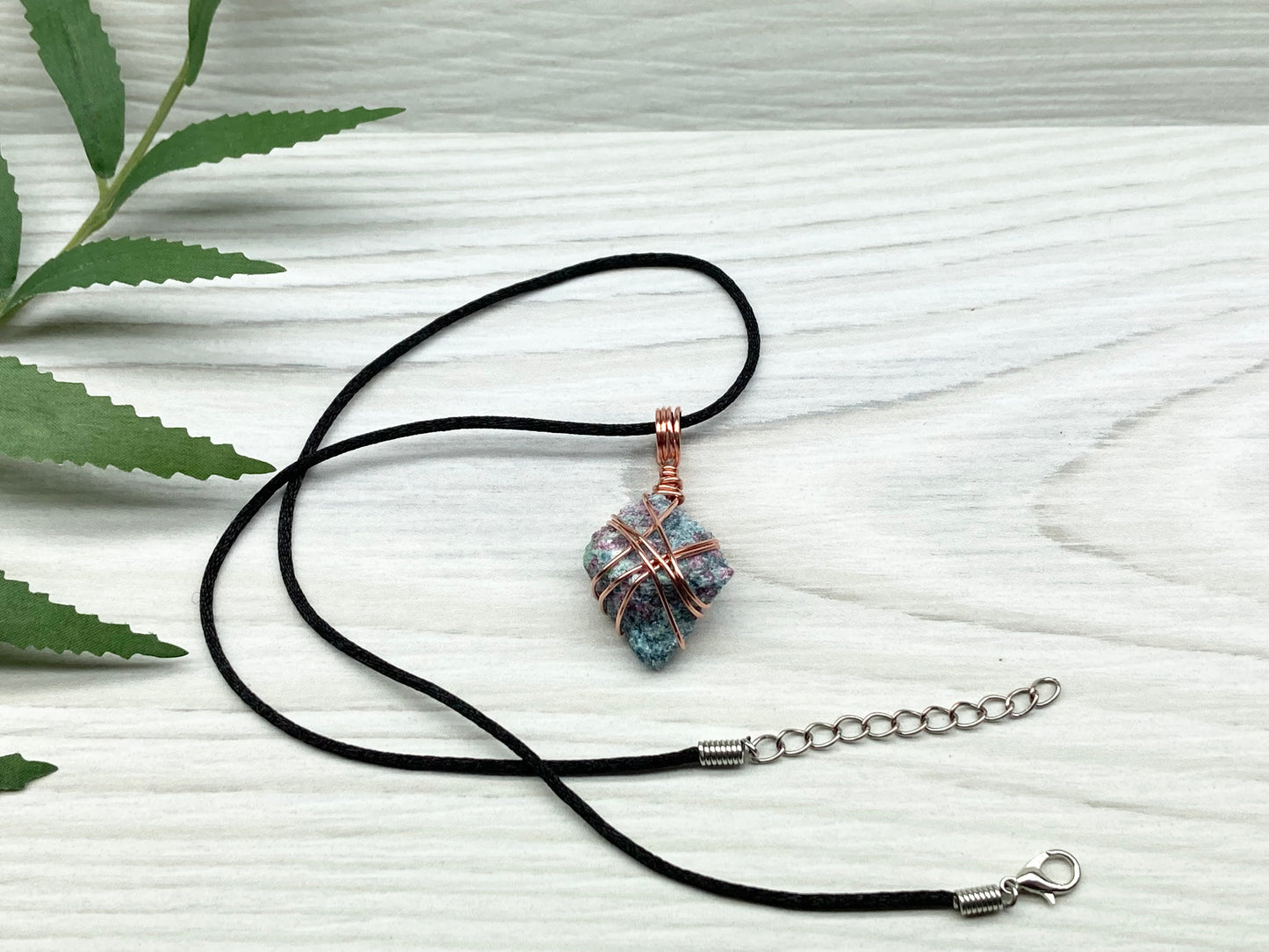 Rough Raw Ruby Zoisite Necklace. This Ruby Zoisite Crystal Is Hand Wrapped With Pure Copper Wire. This Stone is Blue and Red Colored. Gemstone Comes On A Black Chain. Spiritual New Age Style Unisex Jewelry.