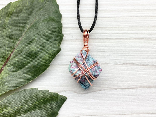 Rough Raw Ruby Zoisite Necklace. This Ruby Zoisite Crystal Is Hand Wrapped With Pure Copper Wire. This Stone is Blue and Red Colored. Gemstone Comes On A Black Chain. Spiritual New Age Style Unisex Jewelry.